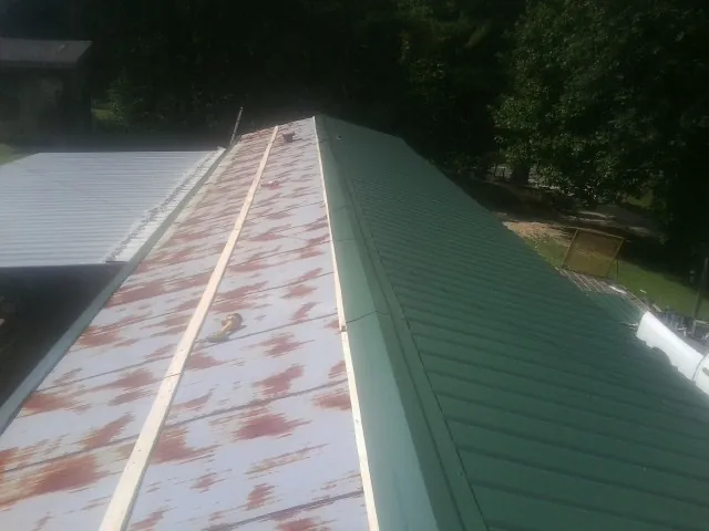 Old rusted panels beside newly installed green metal roofing — Wind Damage Roof Repair by Roofing Brothers in Atlanta